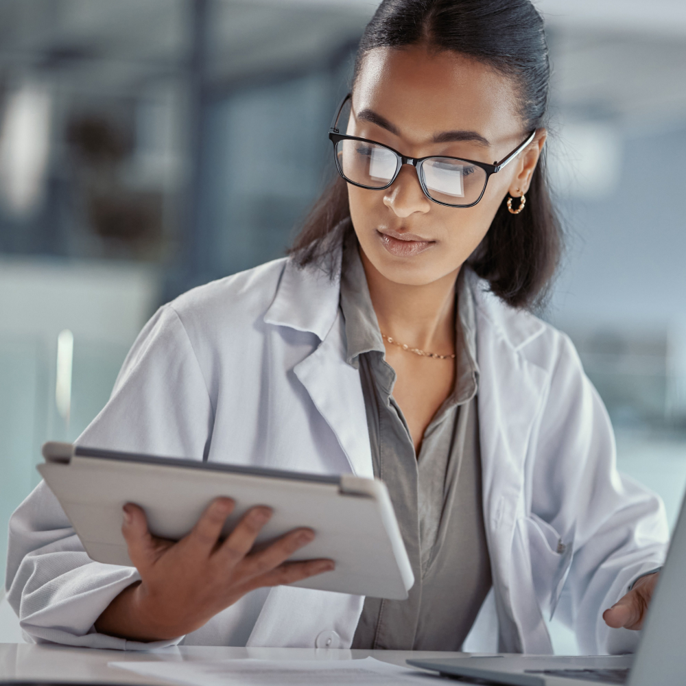 a doctor with glasses looks at an ipad