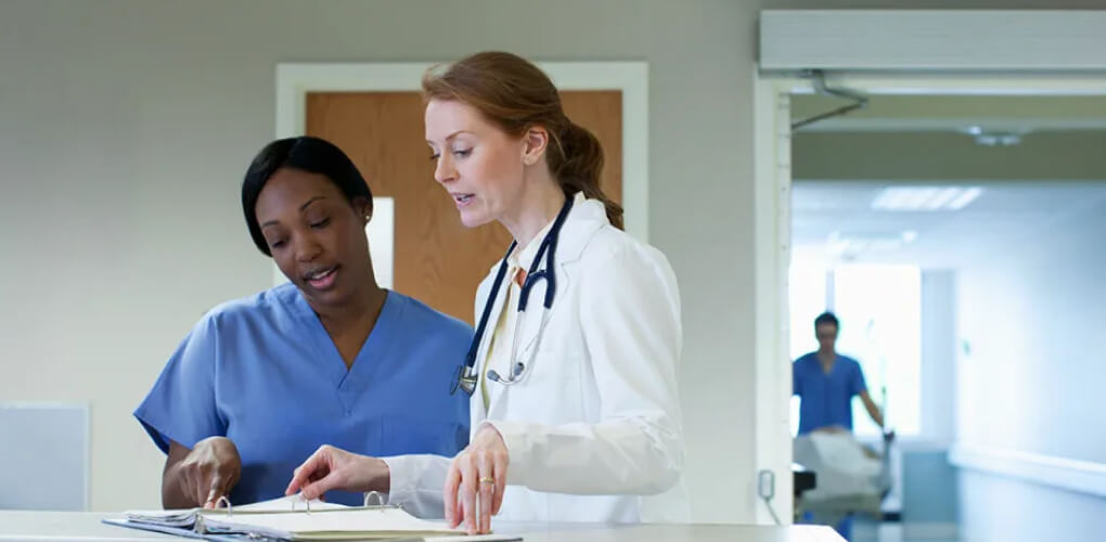 Two medical professionals talking while looking at a chart