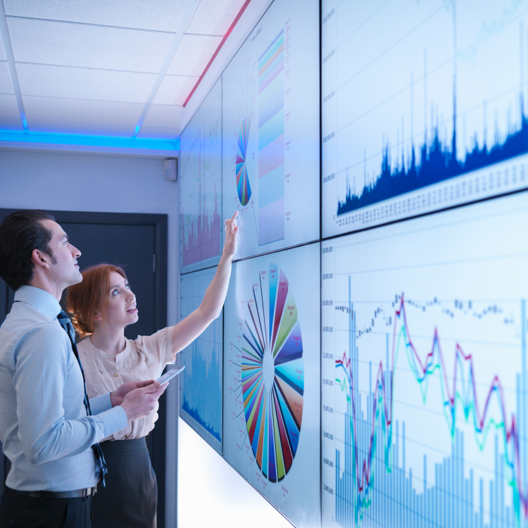 Two people looking at data on a large screen